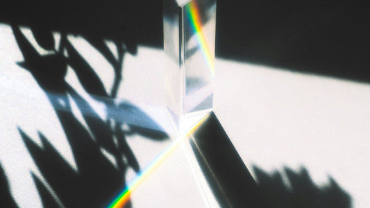 Un prisme de verre posé sur une surface claire décompose un rayon de lumière en un ruban coloré