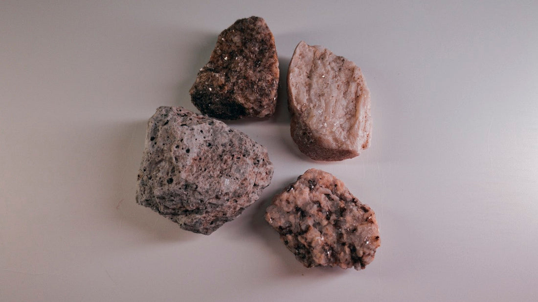 Quatre pierres brutes de tailles et de textures différentes posées sur un fond clair