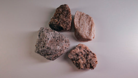 Quatre pierres brutes de tailles et de textures différentes posées sur un fond clair